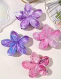 Four colorful flower-shaped hair clips on a light background